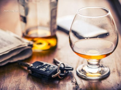 photo of car keys resting on a table next to a snifter of alcohol. DUI Lawyer